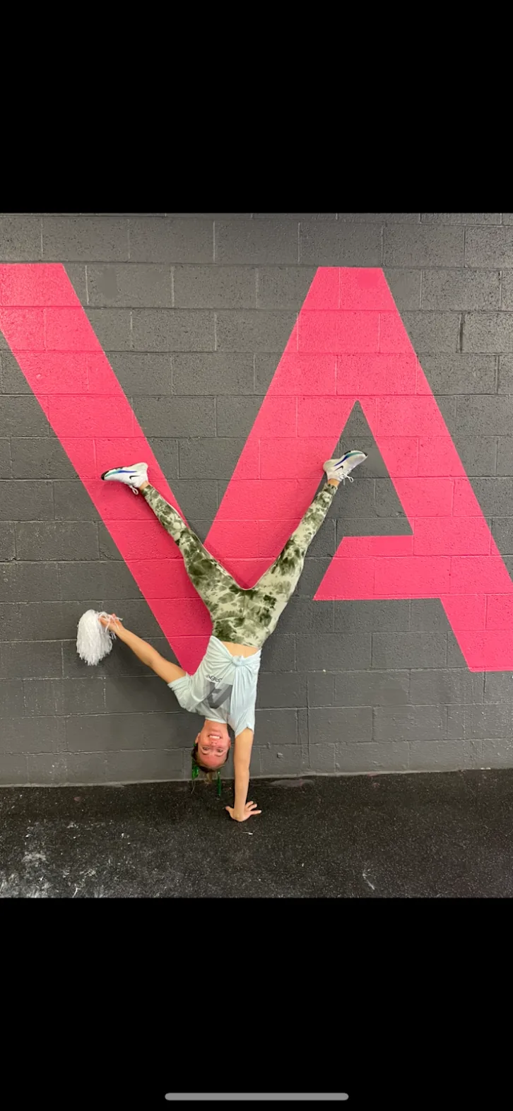 Vickery Athletics member doing a handstand against the pink VA logo wall in East Dallas